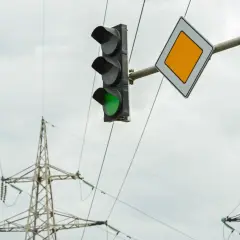 Zielone światło na sygnalizatorze i znak pierwszeństwa wskazują, że można wykonać zawracanie na skrzyżowaniu z sygnalizacją.