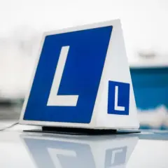 Tablica z literą "L" na dachu samochodu. Zastanawiasz się, ile kosztuje prawo jazdy na raty?