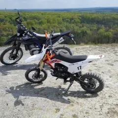 Dwa motocykle crossowe na tle lasu. Czy crossem można jeździć po ulicy? Te maszyny są stworzone do terenu.