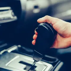 Dłoń trzymająca dźwignię zmiany biegów w samochodzie. Pytanie: czy mając prawo jazdy na automat można jeździć manualem?