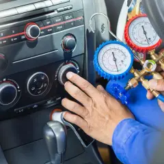 Mechanik sprawdza, ile czynnika do klimatyzacji pozostało w samochodzie, używając manometrów.