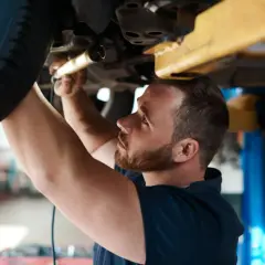 Mechanik sprawdza podwozie auta. Dowiedz się, ile kosztuje badanie techniczne samochodu osobowego.
