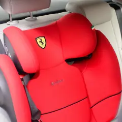 Czerwony fotelik samochodowy Cybex z logo Ferrari, zamontowany za pomocą pasa bezpieczeństwa. Instrukcja jak zamontować fotelik samochodowy.