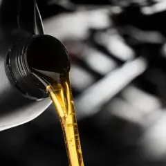Złoty olej silnikowy leje się z czarnego kanistra. Dylemat: który olej lepszy, Castrol czy Motul?