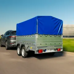 Samochód holuje przyczepkę z niebieską plandeką. Dowiedz się, jak zarejestrować przyczepkę, by podróżować bezpiecznie.