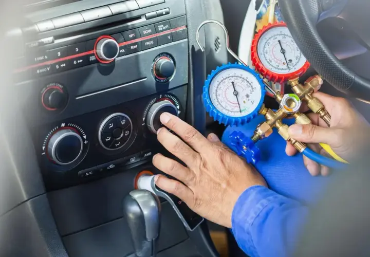 Mechanik sprawdza, ile czynnika do klimatyzacji pozostało w samochodzie, używając manometrów.
