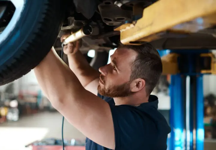 Mechanik sprawdza podwozie auta. Dowiedz się, ile kosztuje badanie techniczne samochodu osobowego.
