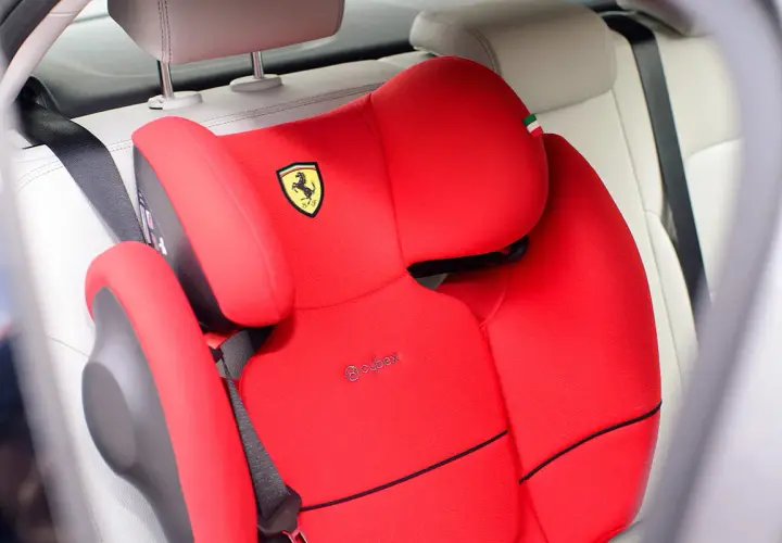 Czerwony fotelik samochodowy Cybex z logo Ferrari, zamontowany za pomocą pasa bezpieczeństwa. Instrukcja jak zamontować fotelik samochodowy.