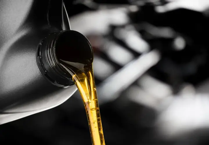 Złoty olej silnikowy leje się z czarnego kanistra. Dylemat: który olej lepszy, Castrol czy Motul?
