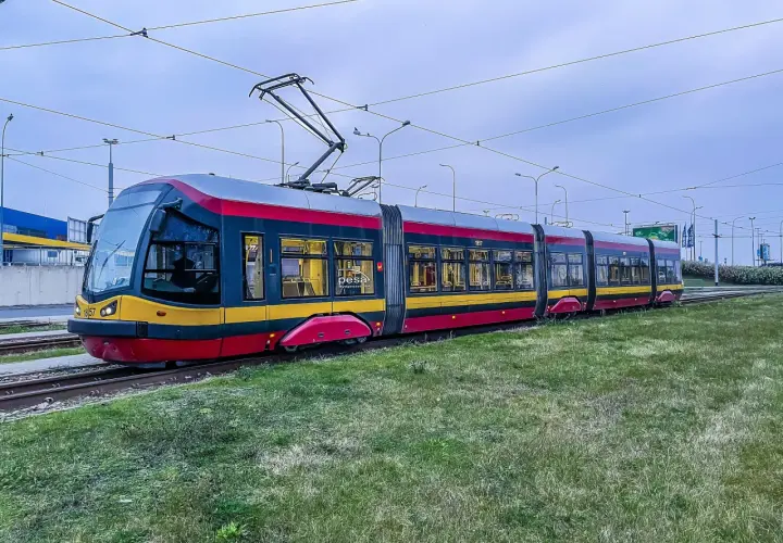 Nowoczesny tramwaj Pesa na torach, otoczony zielenią. Czy tramwaj ma zawsze pierwszeństwo? To pytanie zadaje sobie wielu kierowców.