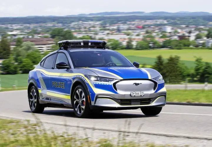 Policyjny Ford Mustang Mach-E z włączonymi sygnałami świetlnymi. Pamiętaj, kiedy można wyprzedzać pojazd uprzywilejowany.