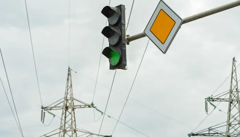 Zielone światło na sygnalizatorze i znak pierwszeństwa wskazują, że można wykonać zawracanie na skrzyżowaniu z sygnalizacją.