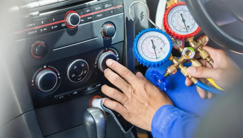 Mechanik sprawdza, ile czynnika do klimatyzacji pozostało w samochodzie, używając manometrów.