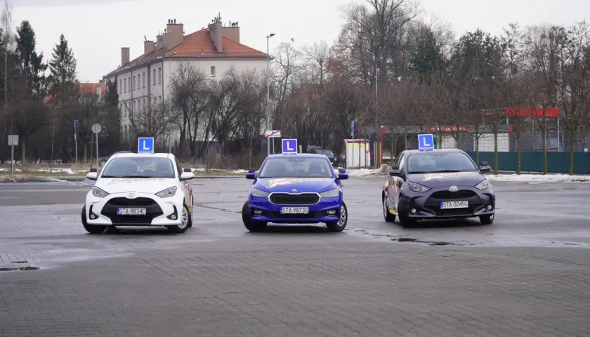 Trzy samochody z literą "L" na dachu, gotowe do nauki jazdy. Idealne do kursu prawa jazdy online.