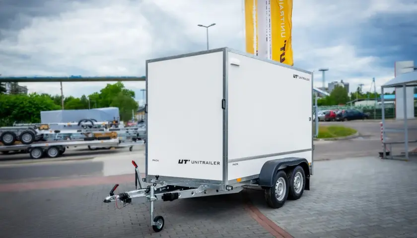 Biała przyczepa towarowa z logo UNITRAILER. Dowiedz się, jak zarejestrować przyczepę rolniczą samoróbkę.