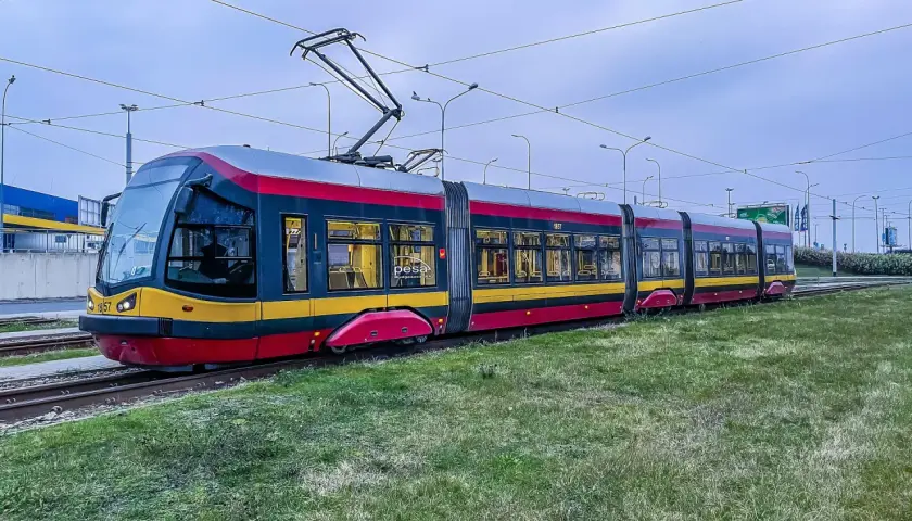 Nowoczesny tramwaj Pesa na torach, otoczony zielenią. Czy tramwaj ma zawsze pierwszeństwo? To pytanie zadaje sobie wielu kierowców.