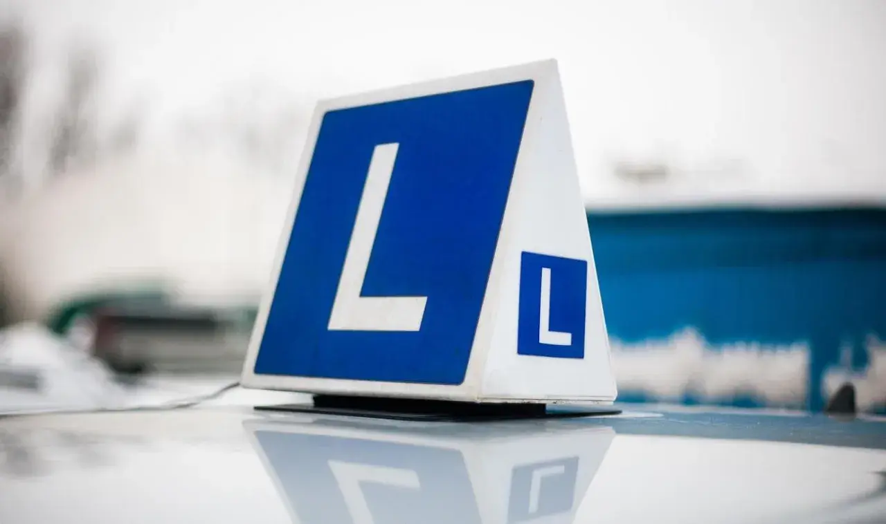 Tablica z literą "L" na dachu samochodu. Zastanawiasz się, ile kosztuje prawo jazdy na raty?