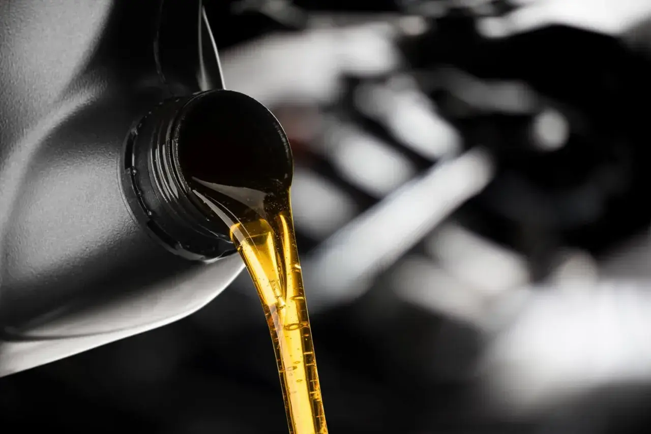 Złoty olej silnikowy leje się z czarnego kanistra. Dylemat: który olej lepszy, Castrol czy Motul?