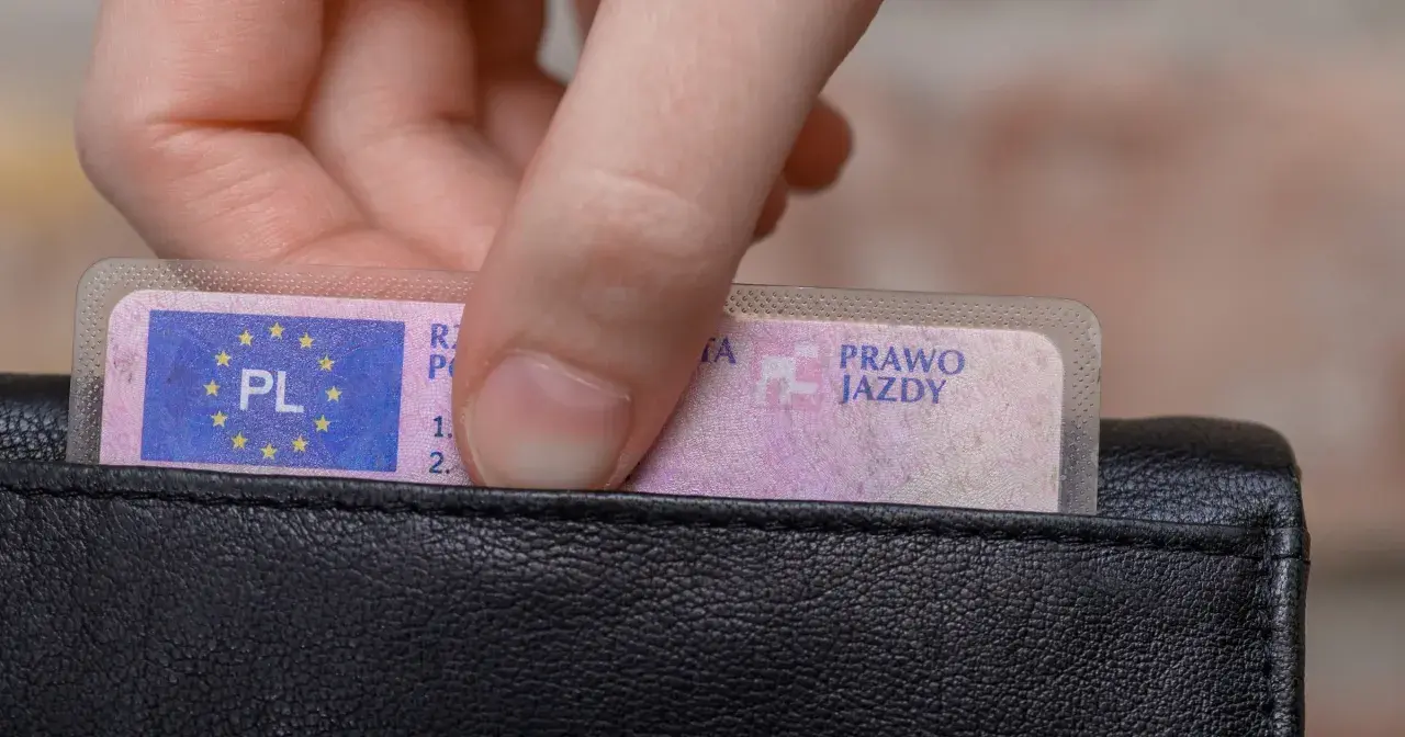 Dłoń wkłada prawo jazdy do portfela. Wkrótce czekają Cię badania lekarskie na prawo jazdy Poznań.