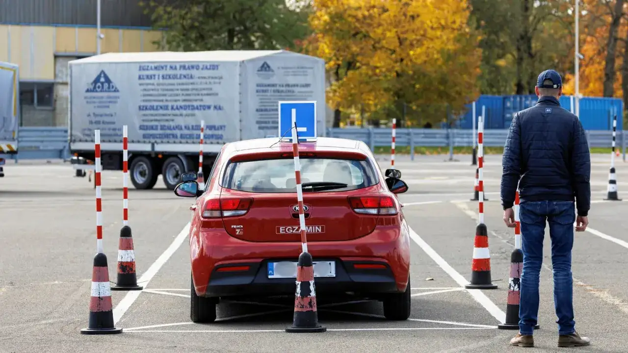 Na placu manewrowym, gdzie odbywa się egzamin na prawo jazdy, czerwony samochód czeka na manewr. Czy egzamin na prawo jazdy jest nagrywany?