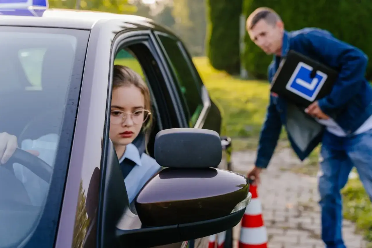 Dziewczyna za kierownicą, instruktor z tablicą