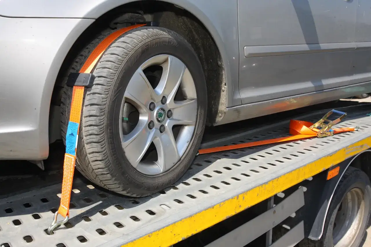 Pomarańczowe pasy mocujące zabezpieczają koło samochodu na lawecie. Dowiedz się, jak zabezpieczyć auto na lawecie, by transport był bezpieczny.
