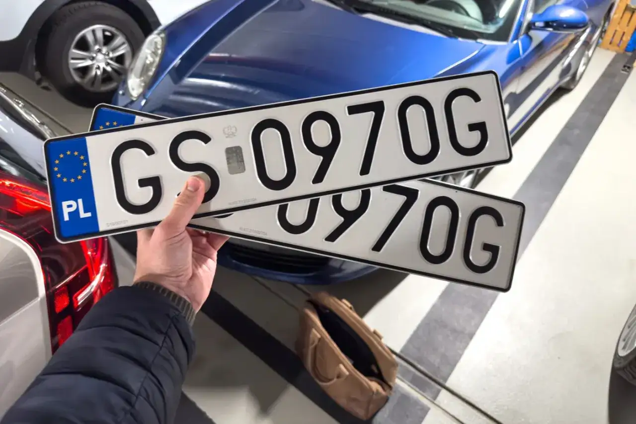 Ręka trzyma tablice rejestracyjne z numerem GS 0970G. Zastanawiasz się, ile jest czasu na przerejestrowanie auta?