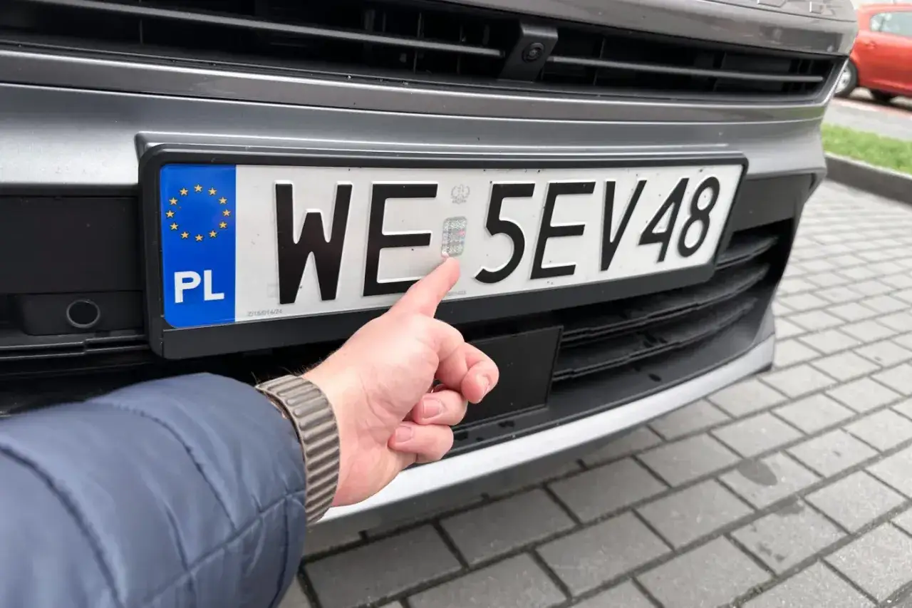 Palec wskazujący na hologram na tablicy rejestracyjnej. Pytanie: ile jest czasu na przerejestrowanie auta?