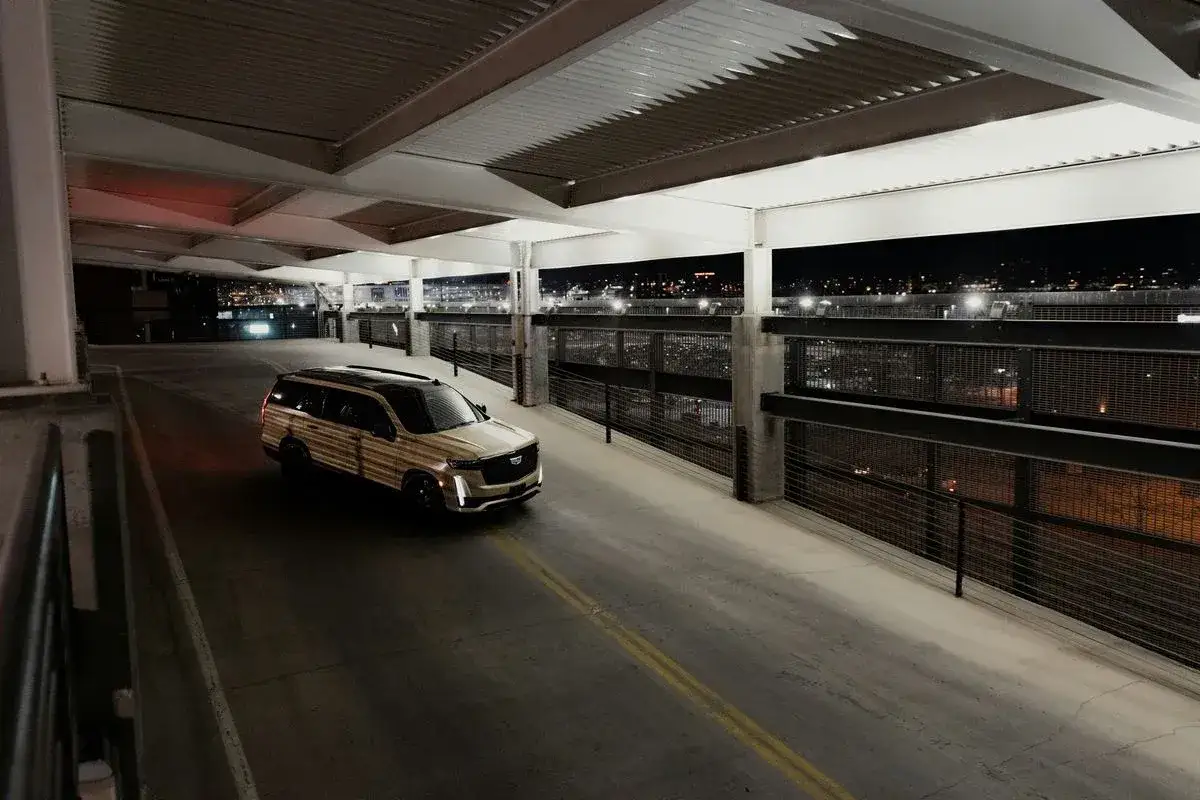 Złoty Cadillac Escalade na parkingu nocą. Zastanawiasz się, ile kosztuje wynajem samochodu tej klasy?
